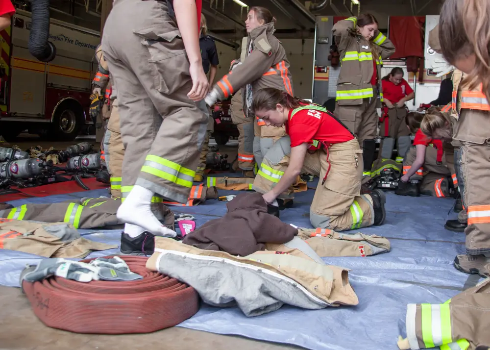 Jeunes cadets pompiers s'équipant de leurs tenues de protection dans une caserne lors d'une formation.