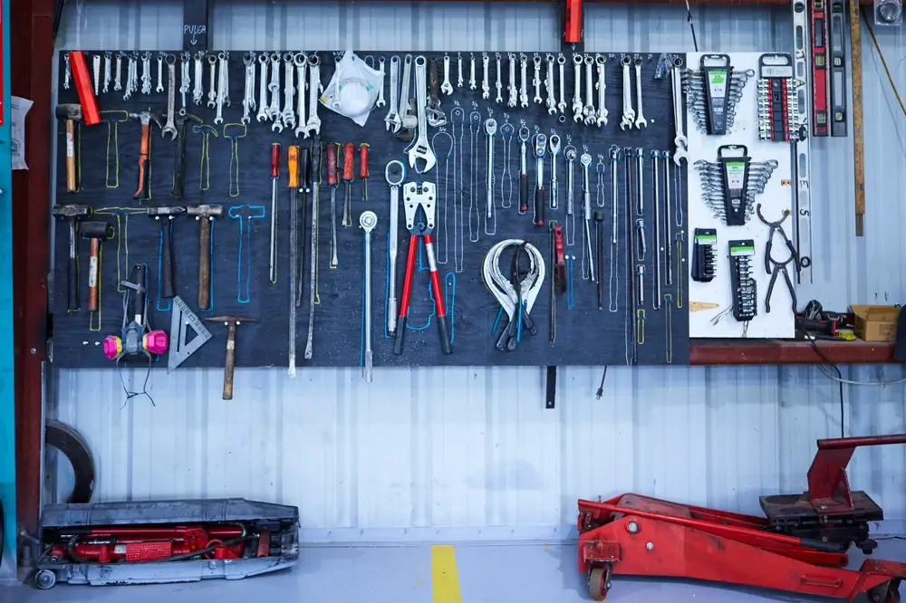 Outils de bricolage manuels et clés organisés sur un établi pour des travaux de menuiserie, plomberie et électricité.