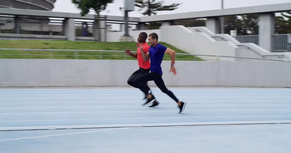Candidats pompiers en plein sprint sur une piste d'athlétisme lors d'un test physique de course chronométré.