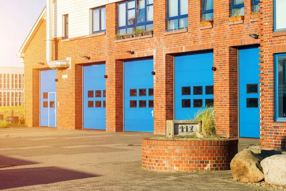 Caserne de pompiers urbaine en briques avec portes bleues et enseigne 112, illustrant les infrastructures du SIAMU.