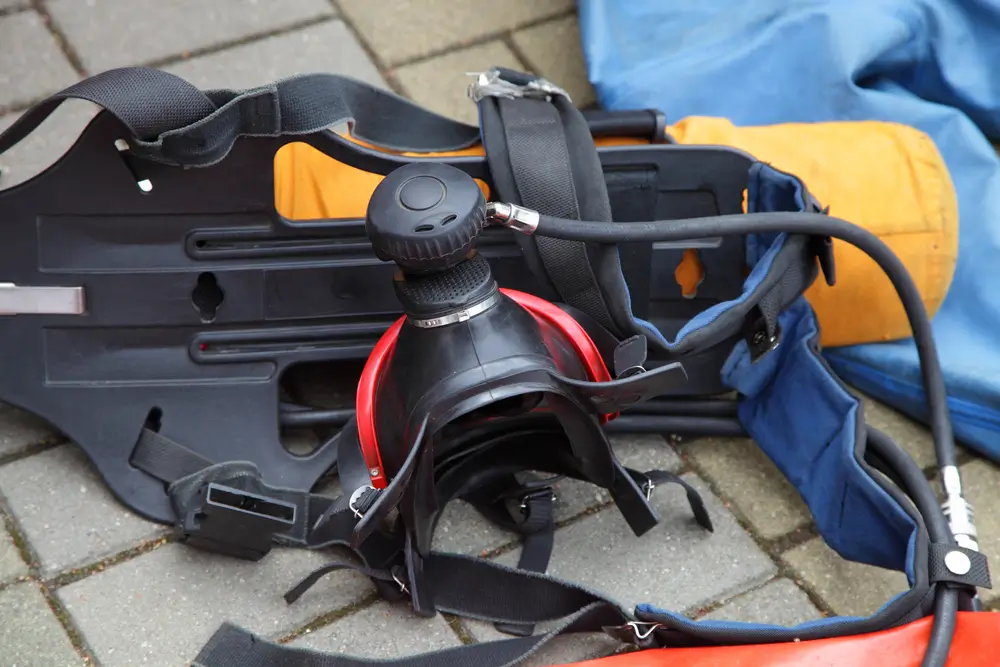 Matériel de plongée de secours des pompiers avec masque facial intégral et bouteille disposés au sol.