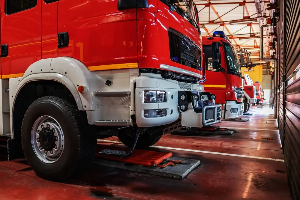 Plusieurs camions rouges stationnés à l'intérieur du garage d'une caserne de pompiers moderne.