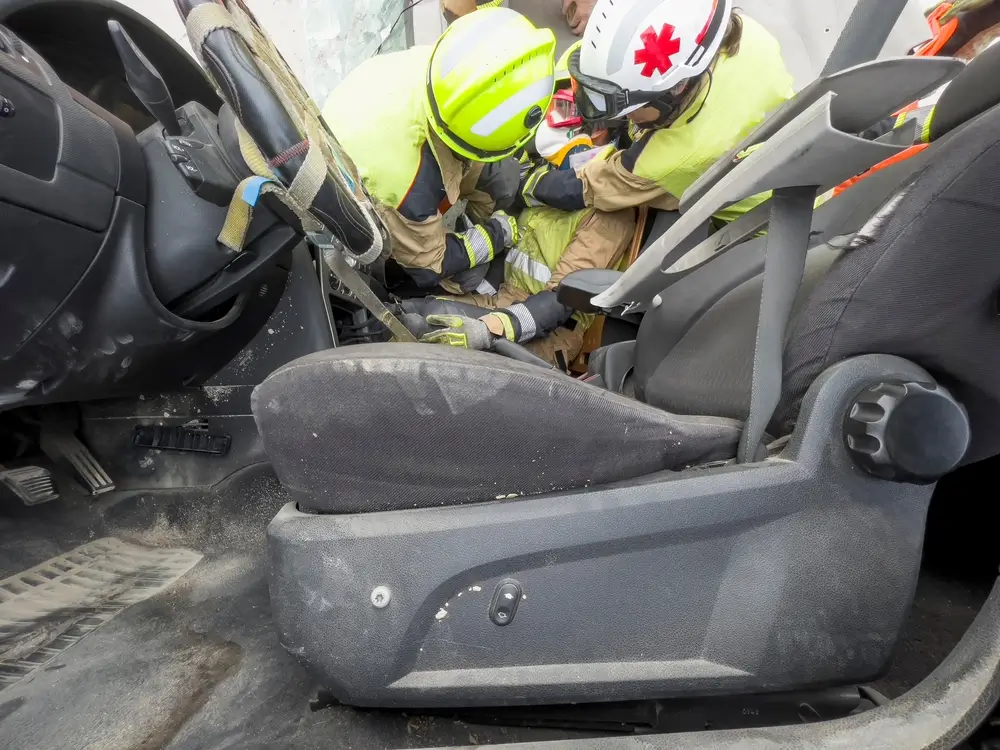 Équipe de pompiers secouristes prodiguant des soins d'urgence à une victime à l'intérieur d'un véhicule accidenté.