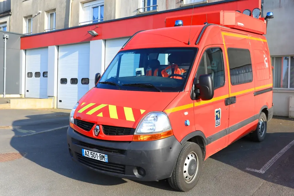 Véhicule d'urgence stationné devant une caserne de pompiers pour les interventions d'aide médicale urgente.