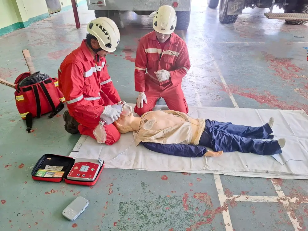 Deux pompiers en formation pratiquent des gestes de secourisme médical sur un mannequin avec un défibrillateur.