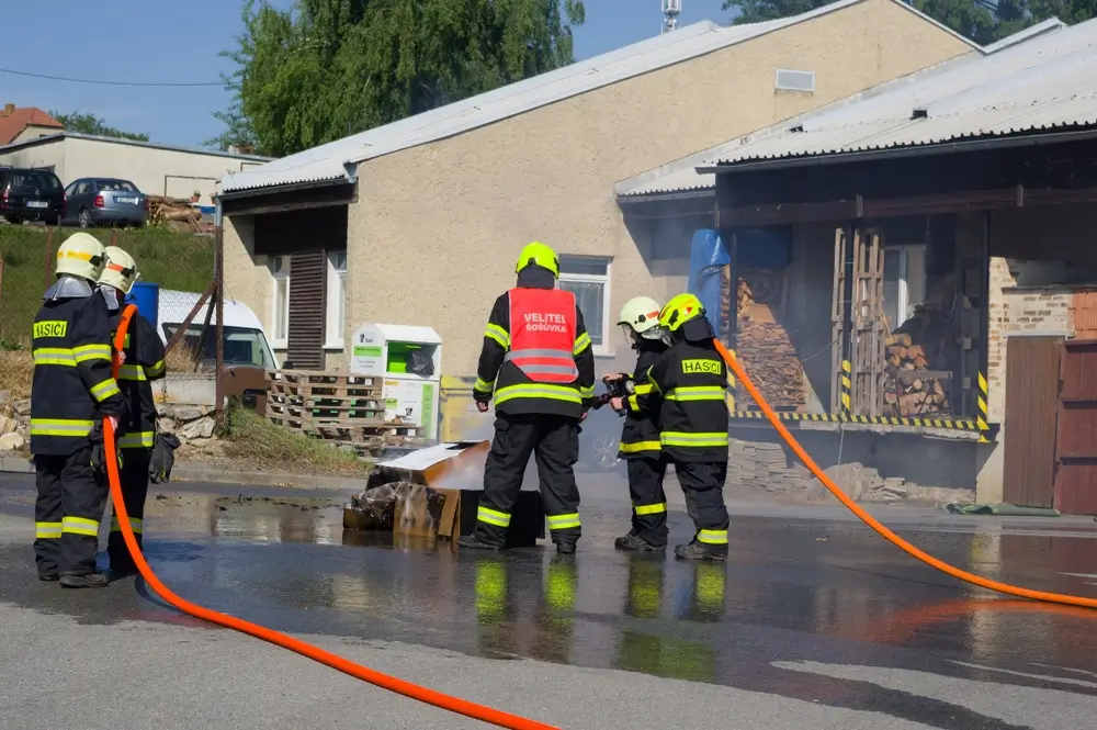 Jeunes sapeurs-pompiers en formation maniant une lance à incendie lors d'un exercice de jeunesse avec un formateur.