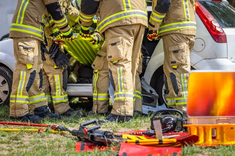 Pompiers en formation pratiquant l'extraction d'une victime avec un plan dur lors d'un exercice de secours routier.