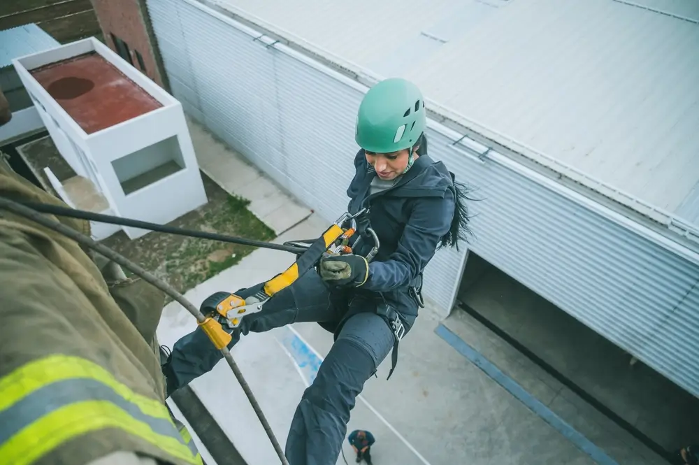 Candidate pompier effectuant une descente en rappel lors d'un test d'aptitude physique pour le recrutement.