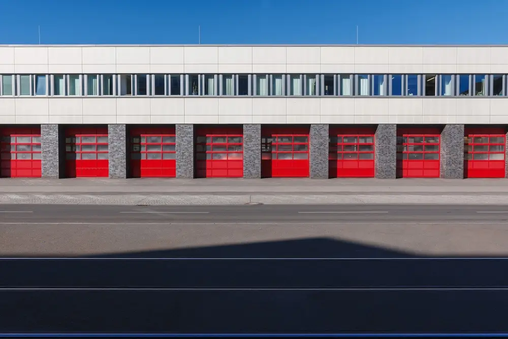 Façade moderne d'une caserne de pompiers montrant l'alignement des portes de garage rouges d'un centre de secours.