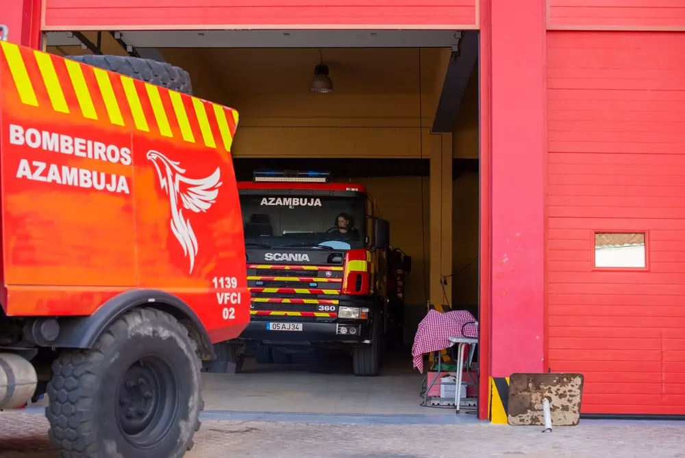 Camions rouges stationnés dans le garage d'une caserne de pompiers moderne avec un pompier prêt pour une intervention.