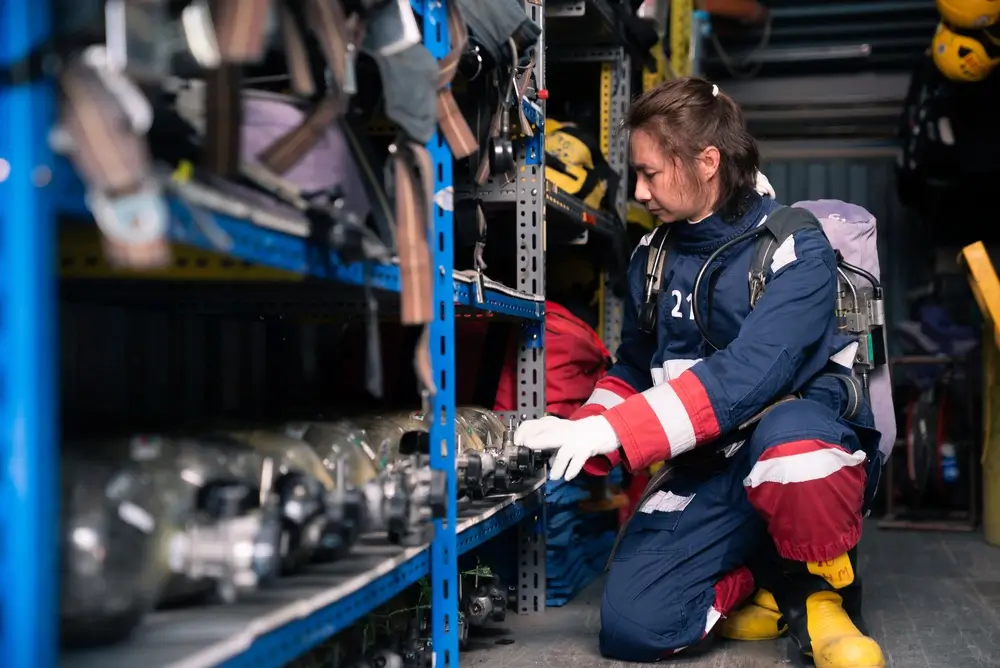 Pompier vérifiant l'équipement de secours et le matériel professionnel dans les rayonnages d'un camion d'intervention.